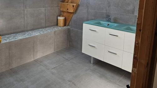 ein Bad mit einem Waschbecken und Fliesenboden in der Unterkunft L'Ecrin - Rubis in Châteaubriant