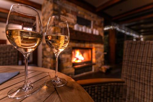 two glasses of white wine sitting on a table with a fireplace at Vila GRAND in Smokovce