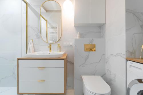 a white bathroom with a sink and a mirror at Flatbook Apartamenty - Jantar Resort in Jantar