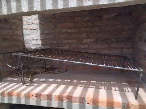 a metal bed sitting against a brick wall at Lo de Yamaha in Aguas Dulces