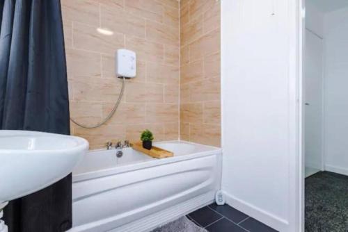 a bathroom with a white tub and a sink at Stunning 3-Bedroom House Sleeps 8 in Liverpool