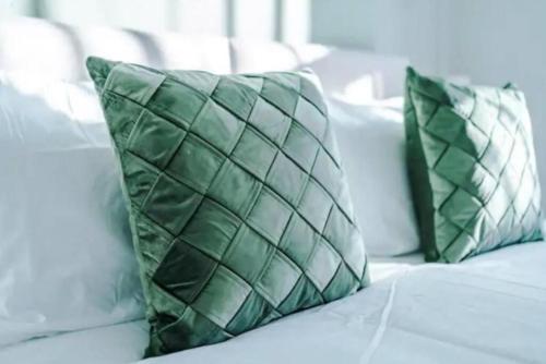 Stunning 3-Bedroom House Sleeps 8 في ليفربول: سرير عليه وسائد خضراء وبيضاء
