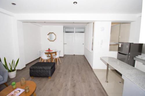 a living room with a table and a kitchen at Basadre Apart Hotel in Tacna