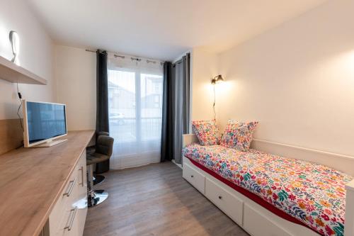 une petite chambre avec un lit et une télévision dans l'établissement Le Rubis - Zenith, à Toulouse