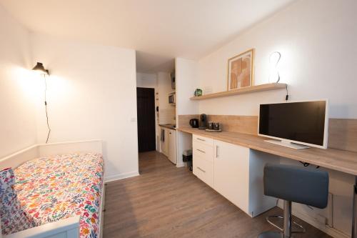 1 dormitorio con 1 cama y escritorio con TV en Le Rubis - Zenith, en Toulouse