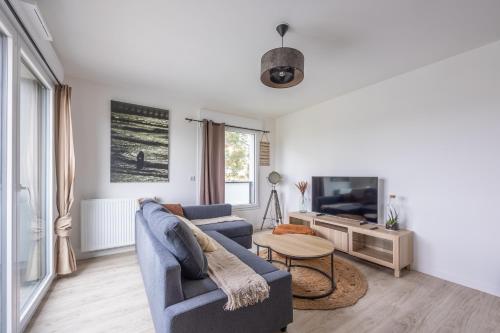 a living room with a blue couch and a tv at L'Edulis - A 100m de la plage et parking privé in Courseulles-sur-Mer