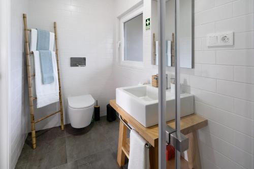 bagno bianco con lavandino e servizi igienici di Rocha do Mar 2 a Biscoitos