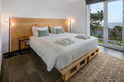 1 dormitorio con 1 cama grande y ventana grande en Rocha do Mar 2, en Biscoitos