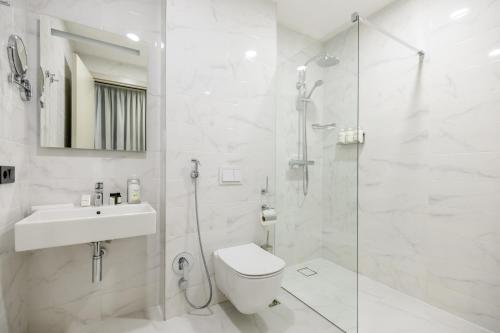a white bathroom with a shower and a toilet and a sink at Brosse Garden in Tbilisi City