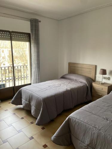 1 dormitorio con 2 camas y ventana grande en APARTAMENTOS LEONOR en Baeza