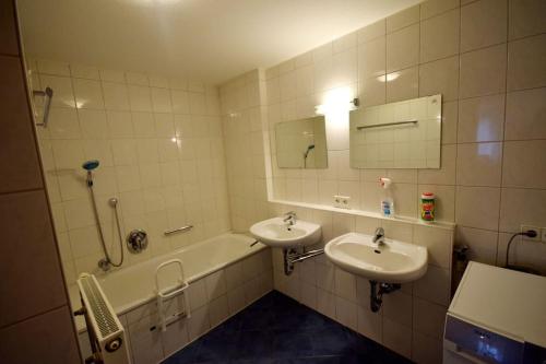 a bathroom with two sinks and a tub and a mirror at Zentral am Wieland-Park mit Aufzug und viel Platz in Biberach an der Riß