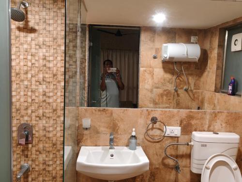 un hombre tomando una foto de un baño con espejo en Rajhans Belliza Aashiana, en Surat