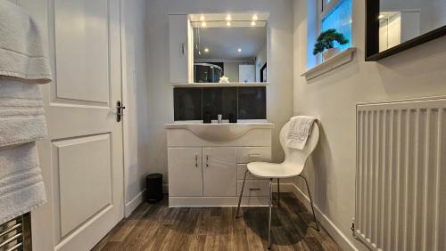 Baño pequeño con lavabo blanco y silla en Ards House Self catering apartment with sea views, en Oban