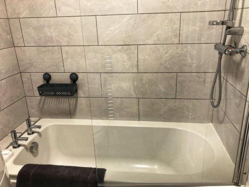 een badkamer met een wit bad en een douche bij Comfort Home From Home Bolton Central Hilden St - Sleeps - 10 in Bolton