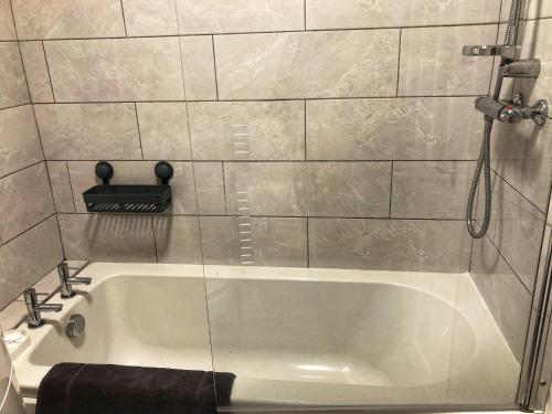 a white bath tub in a bathroom with a shower at Comfortable Home From Home Bolton Central - Sleeps - 10 in Bolton