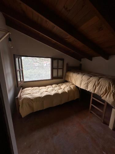 a small room with two beds and a window at Casa La Boticaria in La Cumbrecita