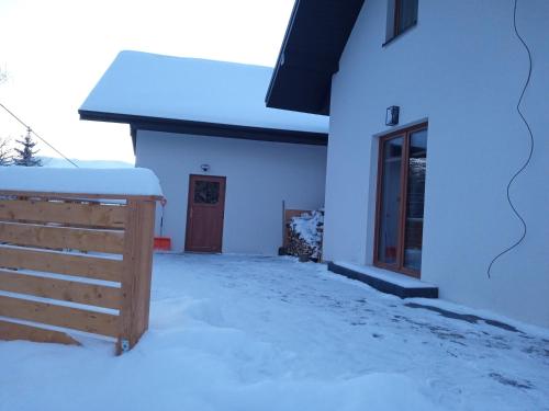 a white house with snow on the ground at Domki Nad Potokiem in Rytro