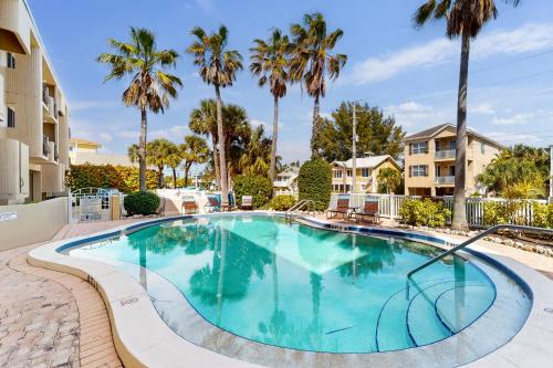 ブレイデントン・ビーチにあるSunset Terrace 206のヤシの木とコンドミニアムがあるスイミングプール