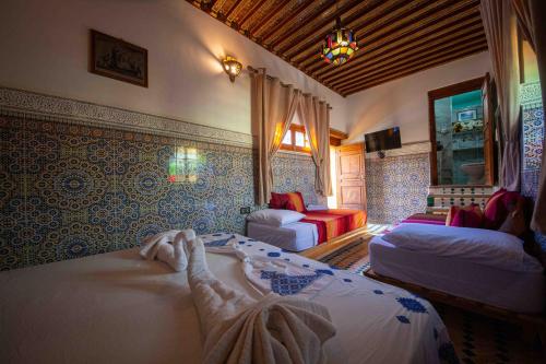 1 dormitorio con 2 camas y sofá en Riad Le Petit Patrimoine De Fés, en Fez