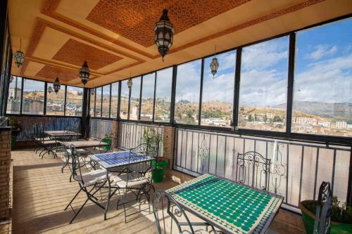 a balcony with tables and chairs and a view of the city at Riad Le Petit Patrimoine De Fés in Fès