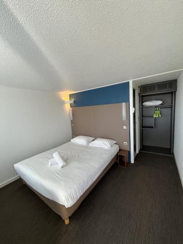 a bedroom with a large bed with a blue headboard at The Originals City, Hôtel Mâcon Nord in Mâcon