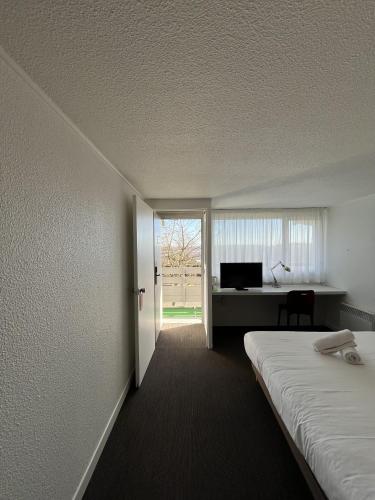a room with a bed and a desk and a window at The Originals City, Hôtel Mâcon Nord in Mâcon