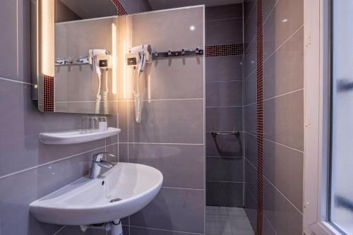 een badkamer met een wastafel en een spiegel bij Grand Hôtel De Turin in Parijs