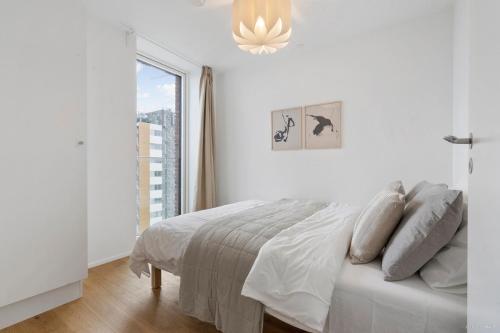 a white bedroom with a bed and a window at Seaside apartment with magical balcony view in Aarhus