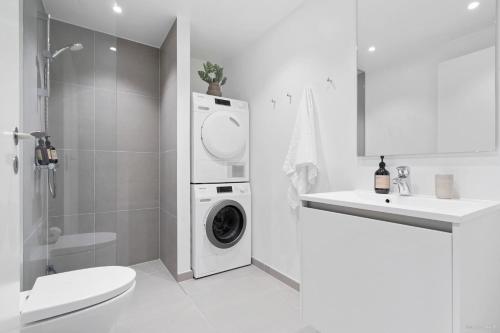 un baño blanco con lavadora y secadora. en Seaside apartment with magical balcony view en Aarhus