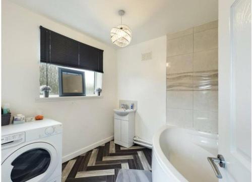 La salle de bains est pourvue d'une baignoire et d'un lave-linge. dans l'établissement Work & Relax - 2 bedroom house with off-road parking, à Swansea