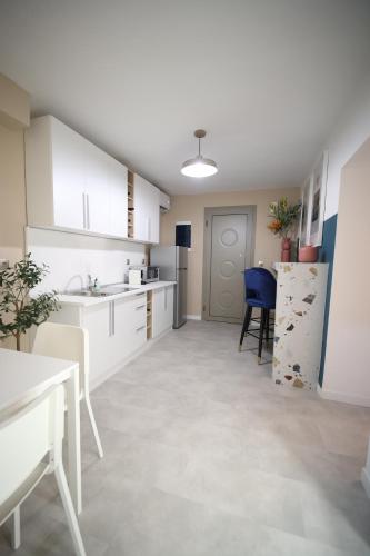 a kitchen with white cabinets and a table and a refrigerator at Ε121 Luxury Suites in Edessa