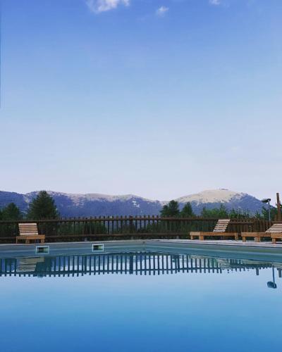 uma grande piscina com montanhas ao fundo em Campeggio Cianabie em Sampeire
