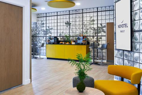 a lobby with a yellow counter and a table at Novotel Paris 17 in Paris