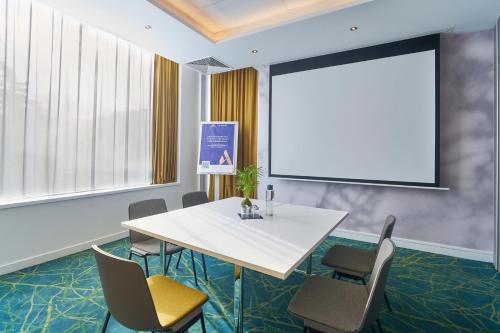 a meeting room with a white table and chairs and a projection screen at Novotel Paris 17 in Paris