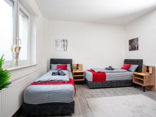 SR24 - Stilvolle Wohnung 2 in Herten في هيرتين: سريرين في غرفة بجدران بيضاء ونافذة