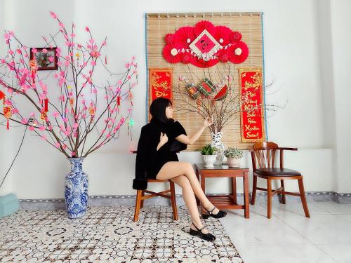 a woman in a black dress sitting at a table in a room at NHÀ NGHỈ PHÚC ANH (cơ sở 1) in Bak Kan