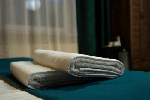 three towels are stacked on top of a bed at Elegant Apartments in Poznań
