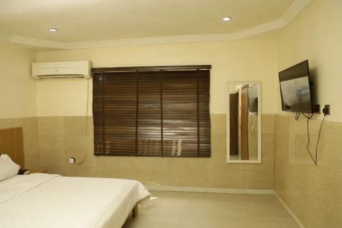 a bedroom with a bed and a window with a television at CALBERT LODGE in Abuja