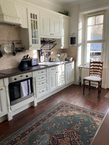 - une cuisine avec des placards blancs et un tapis dans l'établissement Maison de ville, à Broons