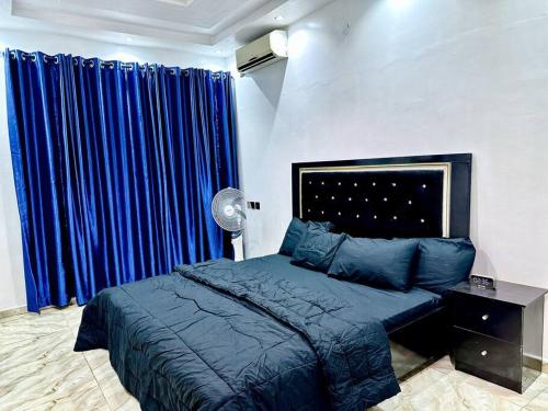 Schlafzimmer mit blauem Bett und blauen Vorhängen in der Unterkunft Sweet Serenity with Ecstatic Views in Lagos