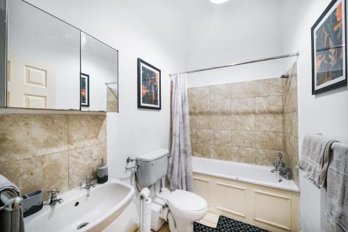 a bathroom with a toilet and a tub and a sink at Relaxing Flat in London - Sleeps 6 - Garden in Greenford