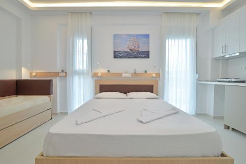 a white bedroom with a large bed and a kitchen at Evas Rooms in Nei Poroi