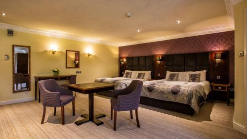 a hotel room with a bed and a table and chairs at Waterton Park Hotel in Wakefield