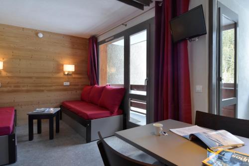 un salon avec un canapé rouge et une table dans l'établissement travelski home select - Résidence 3000, à La Plagne Tarentaise