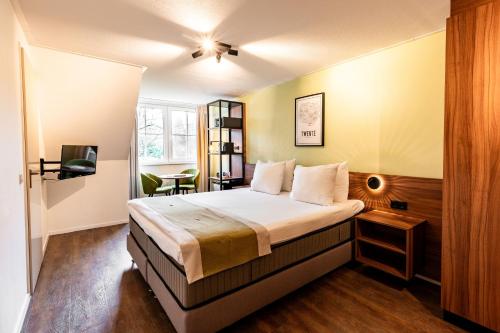een slaapkamer met een bed en een tv. bij Landhuis Hotel de Herikerberg in Markelo