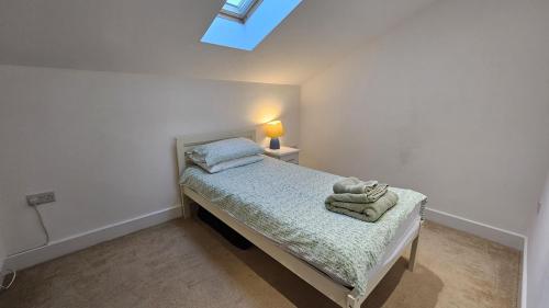 a small bedroom with a bed with a lamp and towels at Stable Barn Apartment in Saint Breward