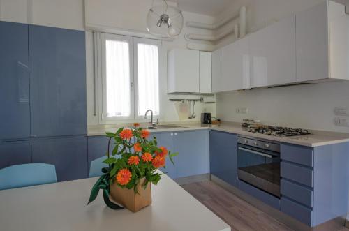 una cucina con armadi blu e un vaso con fiori arancioni di FRONTE MARE a Pesaro
