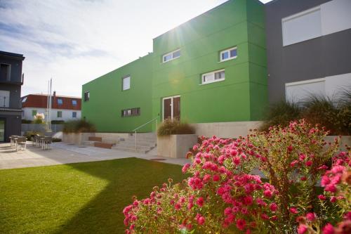 a green building with pink flowers in a yard at Good Rooms GmbH Guntramsdorf in Guntramsdorf