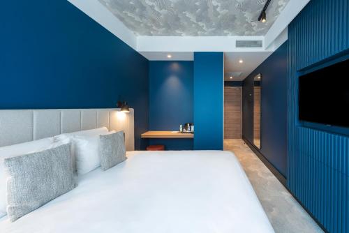 a bedroom with a large bed with a blue wall at KYRIAD LYON OUEST Limonest in Limonest