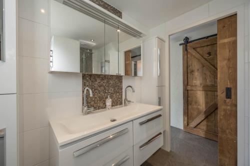 La salle de bains est pourvue d'un lavabo et d'une porte en bois. dans l'établissement Meerzicht 71 - Perfectly suited for 6 persons, à Uitgeest